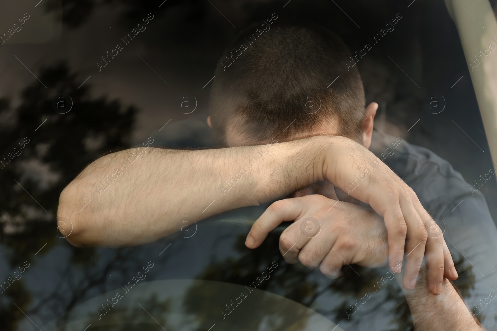 Photo of Tired man sleeping on steering wheel in his car, view from outside