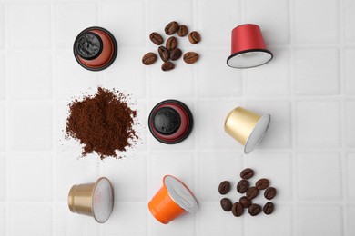 Many coffee capsules, powder and beans on white tiled table, flat lay