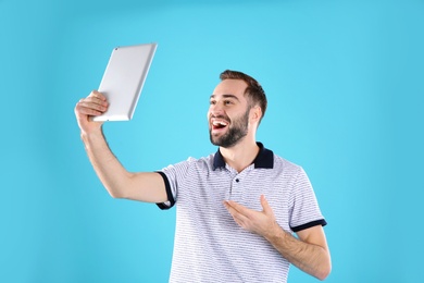 Man using tablet for video chat on color background