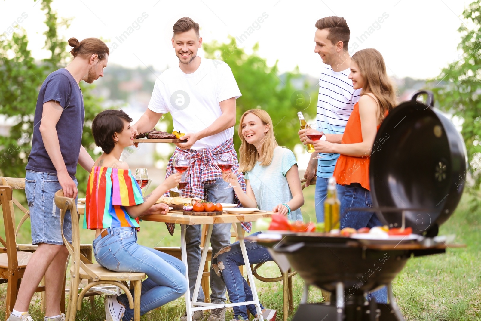 Photo of Young people having barbecue with modern grill outdoors