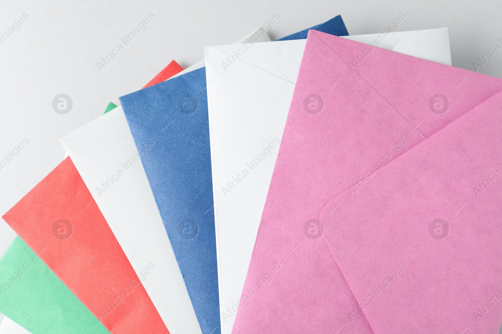 Photo of Colorful paper envelopes on light background, top view