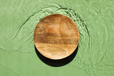 Photo of Presentation for product. Wooden podium in water on green background, top view