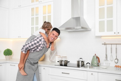 Little girl with her father cooking together in modern kitchen