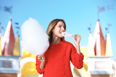 Photo of Young cheerful woman having fun with  cotton candy in amusement park