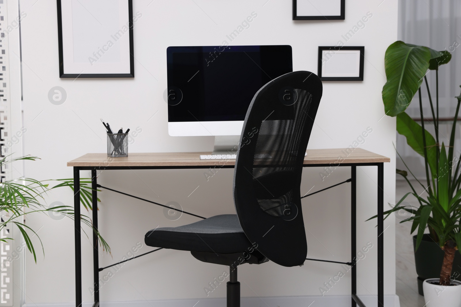 Photo of Comfortable office chair near desk in modern workplace