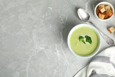 Delicious broccoli cream soup served on grey marble table, flat lay. Space for text