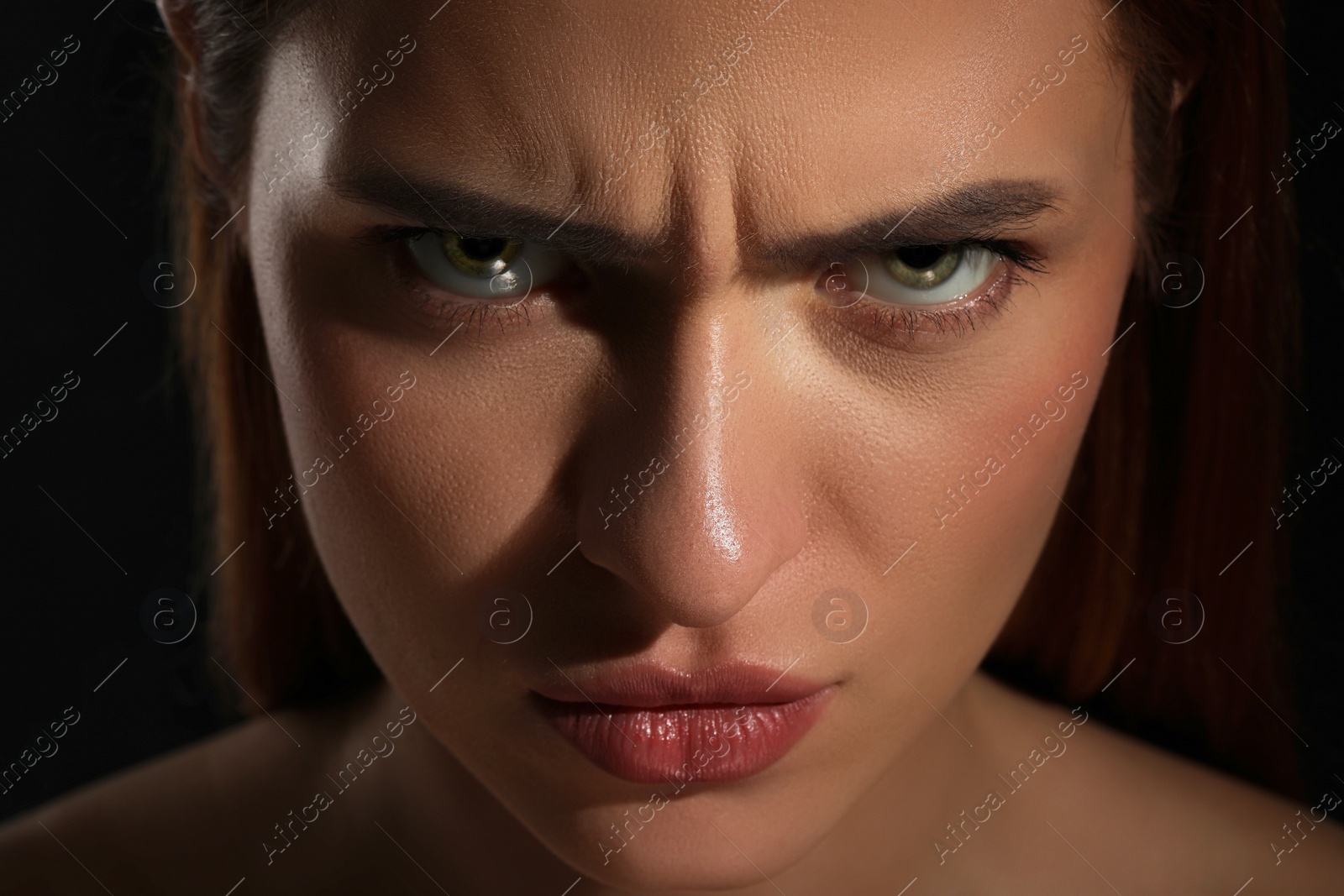 Photo of Evil eye. Young woman with scary eyes on black background, closeup