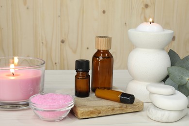 Photo of Different aromatherapy products and burning candles on white wooden table