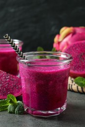 Photo of Delicious pitahaya smoothie, fruit and fresh mint on grey table