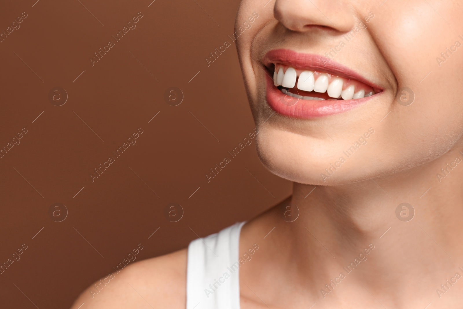 Image of Woman with diastema between upper front teeth on brown background, closeup