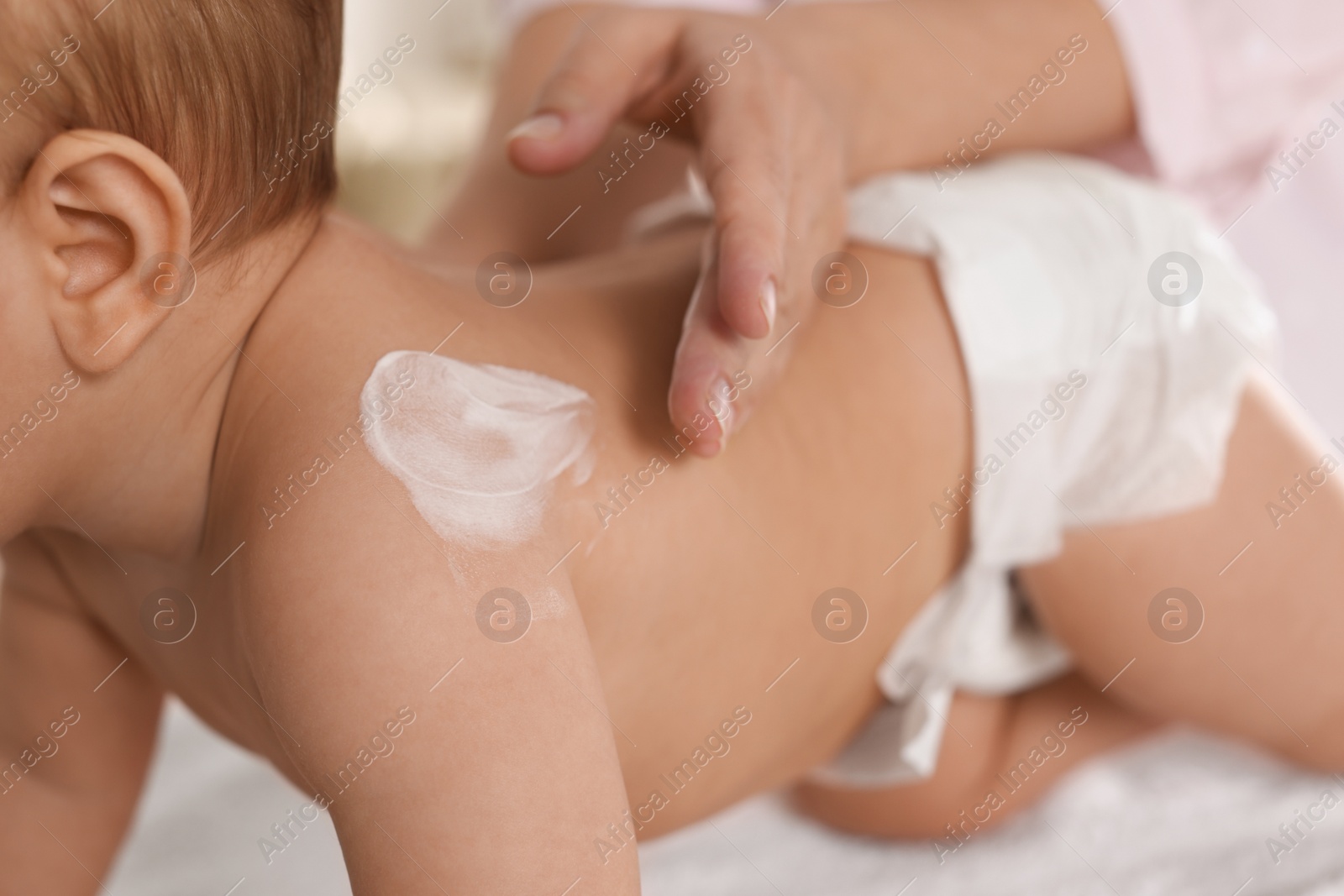 Photo of Mother applying body cream on her little baby, closeup