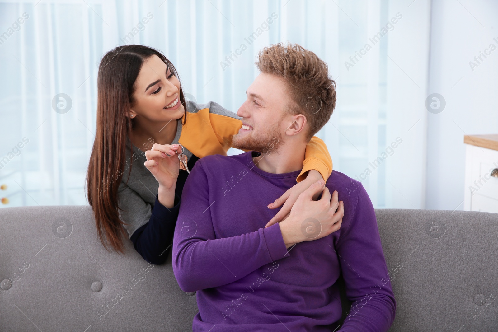 Photo of Young couple with key from their new house indoors. Moving day