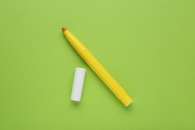 Photo of Bright yellow marker and cap on light green background, flat lay