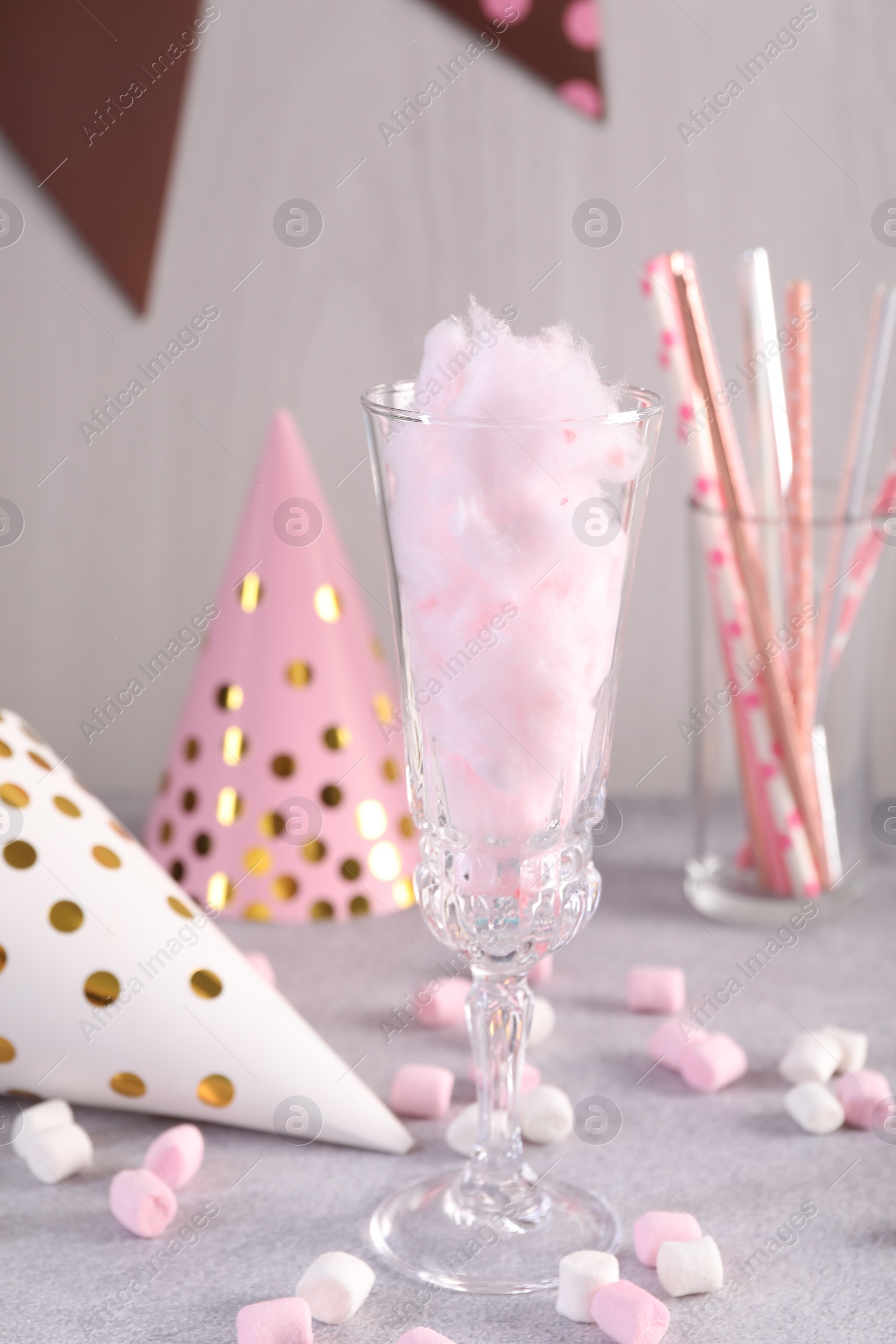 Photo of Tasty cotton candy cocktail in glass, festive decor and marshmallows on gray table
