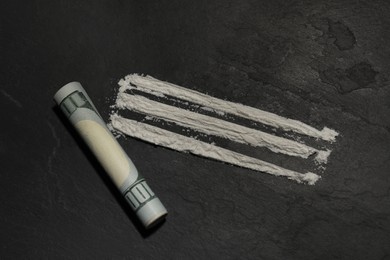 Photo of Drug addiction. Cocaine and rolled dollar banknote on grey textured background,, flat lay