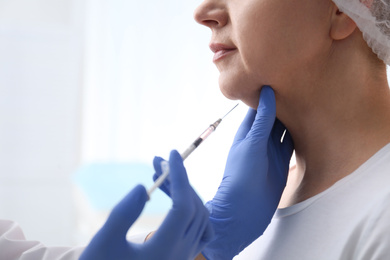Photo of Mature woman with double chin receiving injection in clinic, closeup
