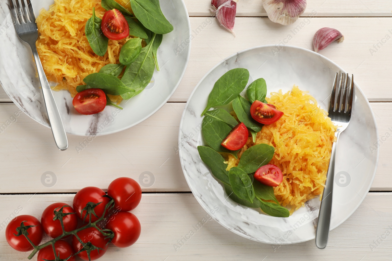 Photo of Tasty spaghetti squash with tomatoes and basil served on white wooden table, flat lay