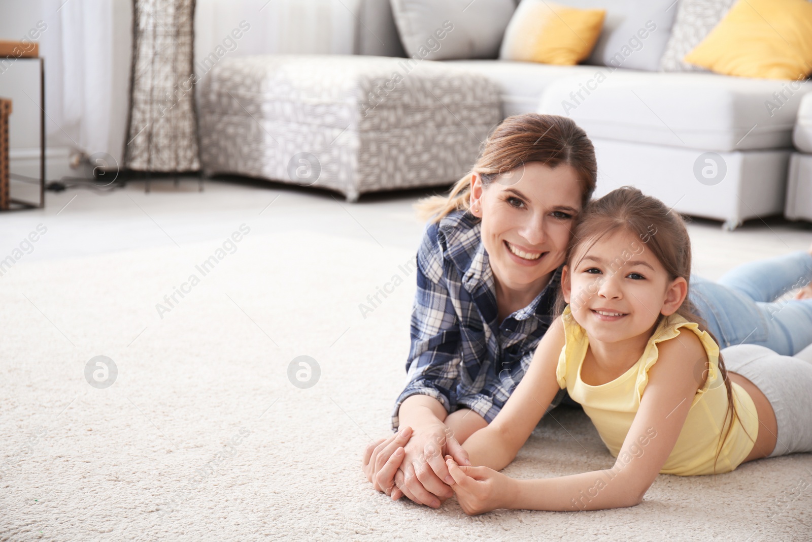 Photo of Cute little girl and her mother lying on cozy carpet at home