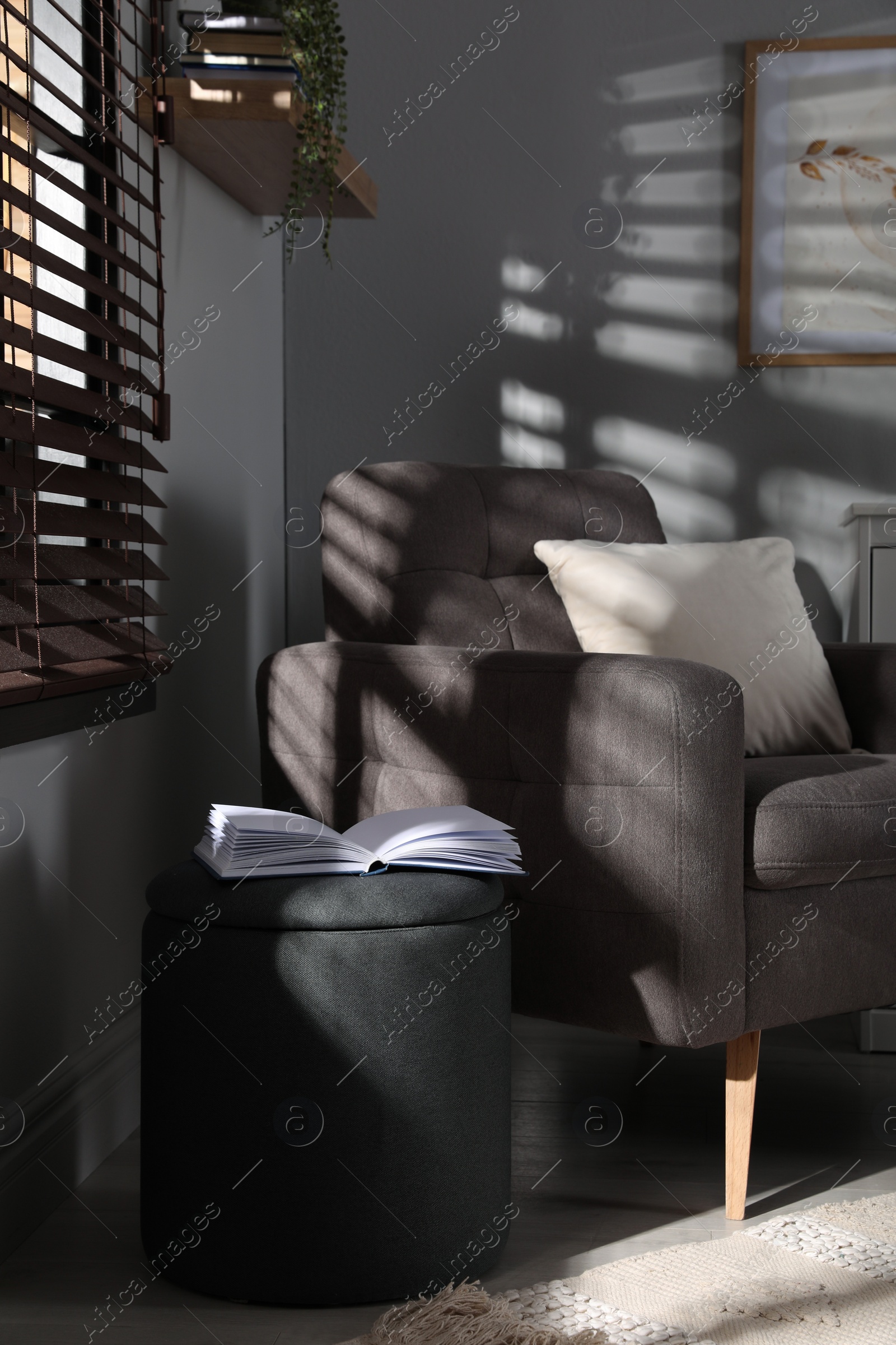 Photo of Stylish dark grey pouf and armchair in room. Home design