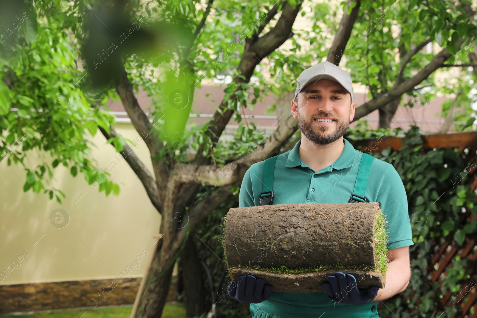 Photo of Worker holding rolled grass sod in garden, space for text