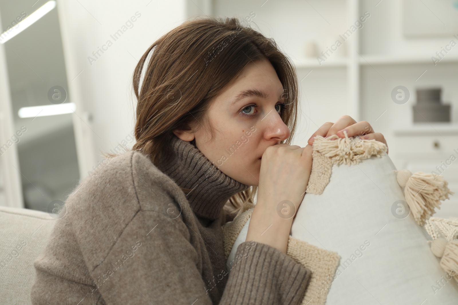 Photo of Sad young woman sitting on sofa at home