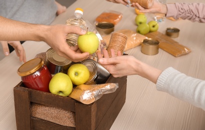 Photo of Volunteers taking food out of donation box on table, closeup