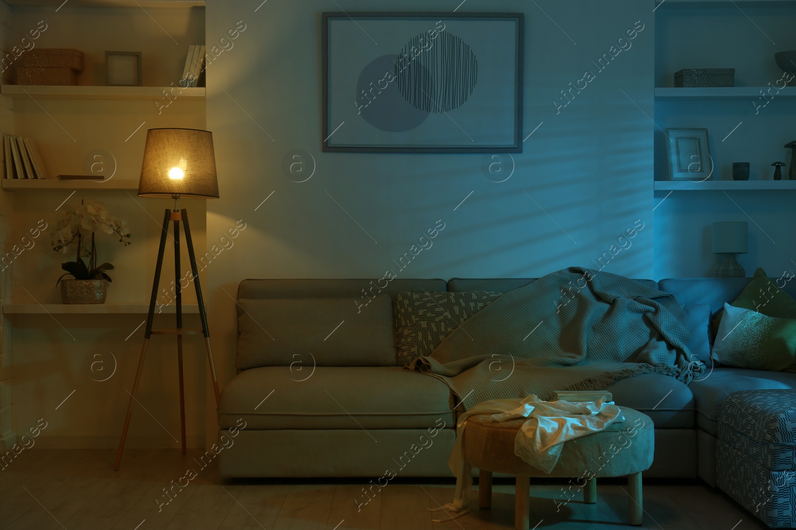 Photo of Stylish room interior with couch and lamp at night