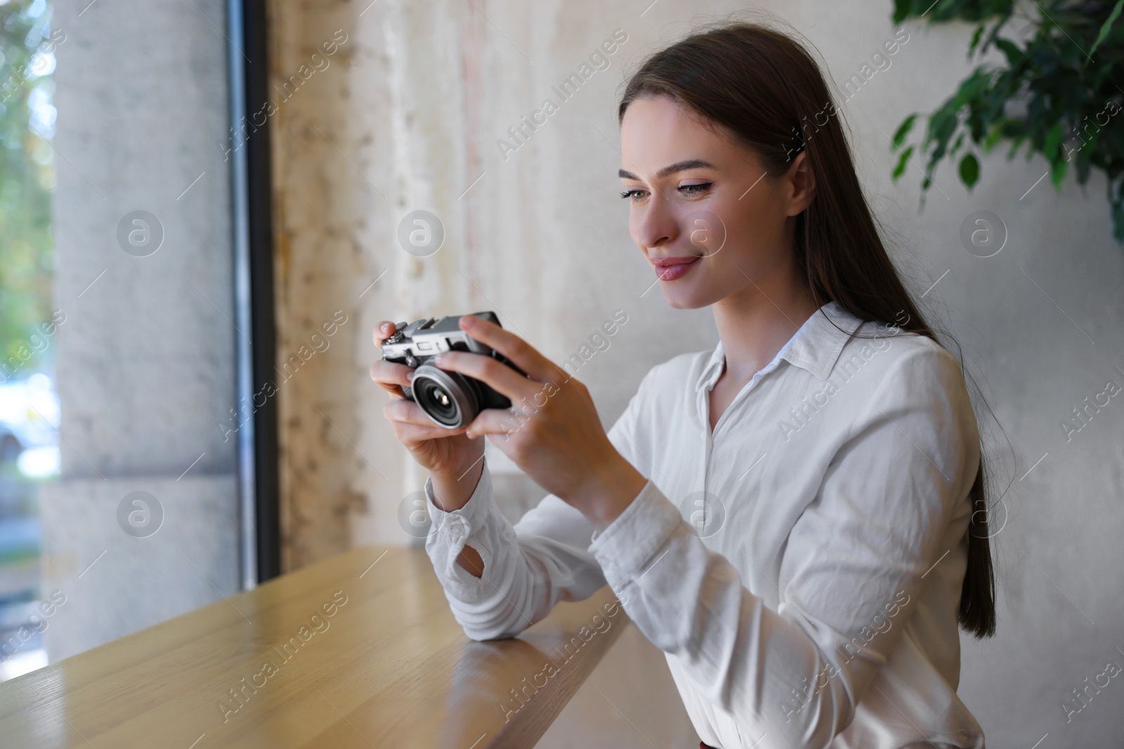 Photo of Young woman taking photo at cafe, space for text. Creative hobby