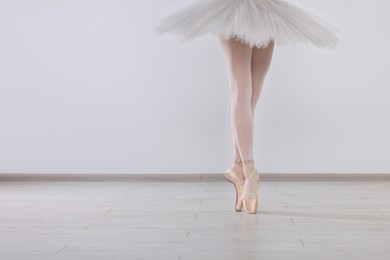 Photo of Young ballerina in pointe shoes practicing dance moves at studio, closeup. Space for text
