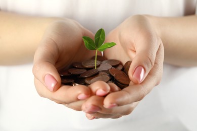 Photo of Woman holding many coins with green sprout on white background, closeup. Investment concept