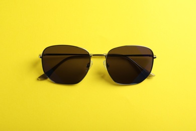 Photo of Stylish sunglasses on yellow background, top view