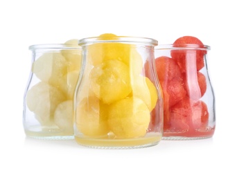 Glass jars of melon and watermelon balls on white background