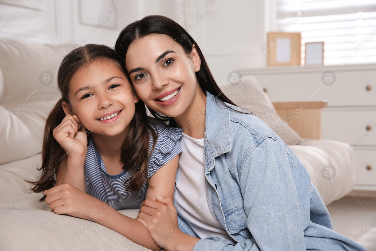 Photo of Young mother and her daughter on sofa in living room. Adoption concept