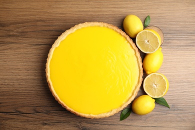 Photo of Delicious homemade lemon pie and fresh fruits on wooden table, flat lay