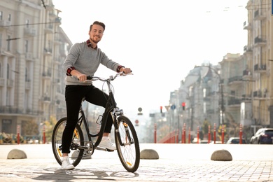 Handsome happy man riding bicycle on city street