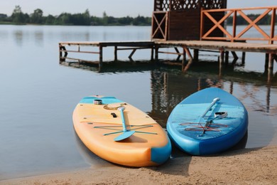 Photo of SUP boards with paddles on river shore