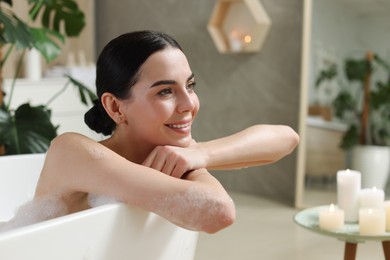 Beautiful young woman taking bubble bath at home