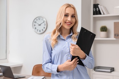 Portrait of happy secretary with clipboard in office