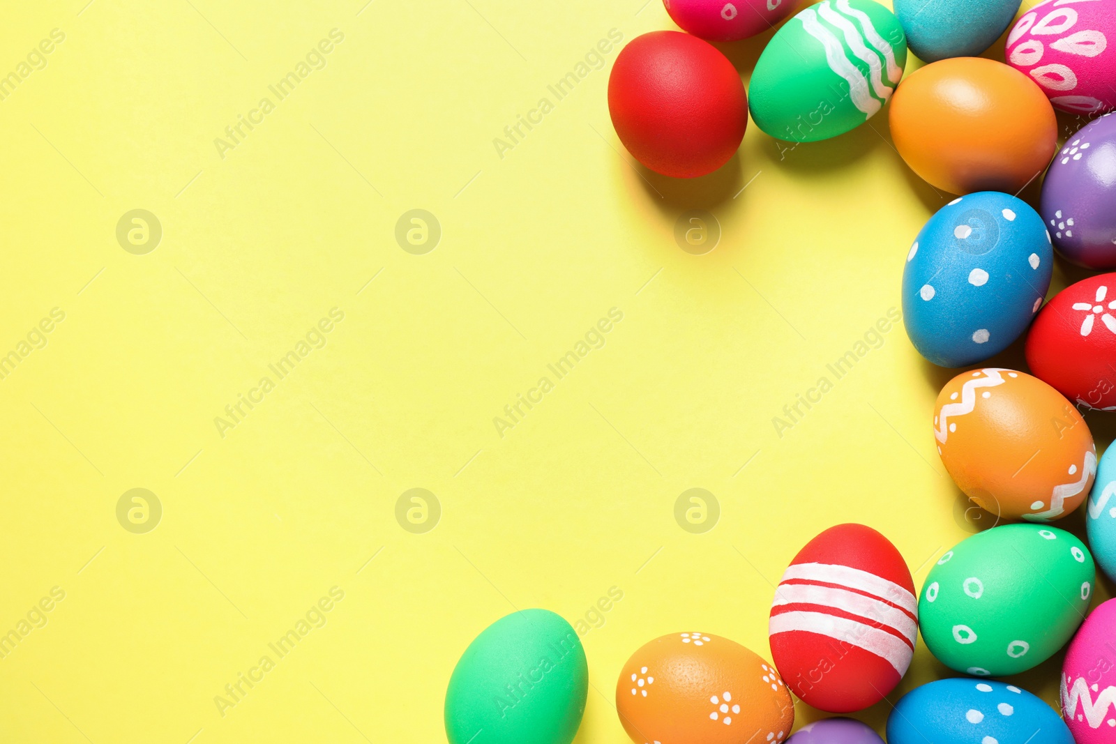 Photo of Colorful Easter eggs on yellow background, flat lay. Space for text