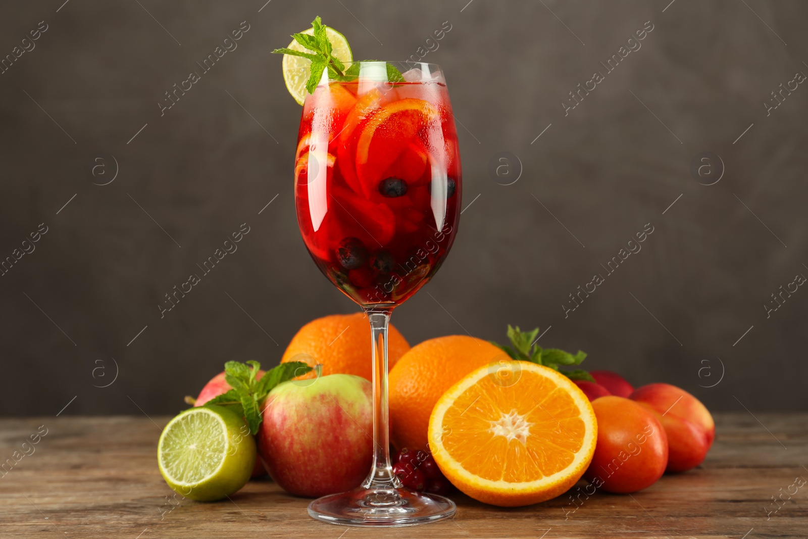 Photo of Glass of Red Sangria and fruits on wooden table