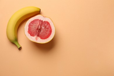 Photo of Banana and half of grapefruit on pale orange background, flat lay with space for text. Sex concept