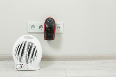 Photo of Modern electric compact and fan heaters indoors, space for text