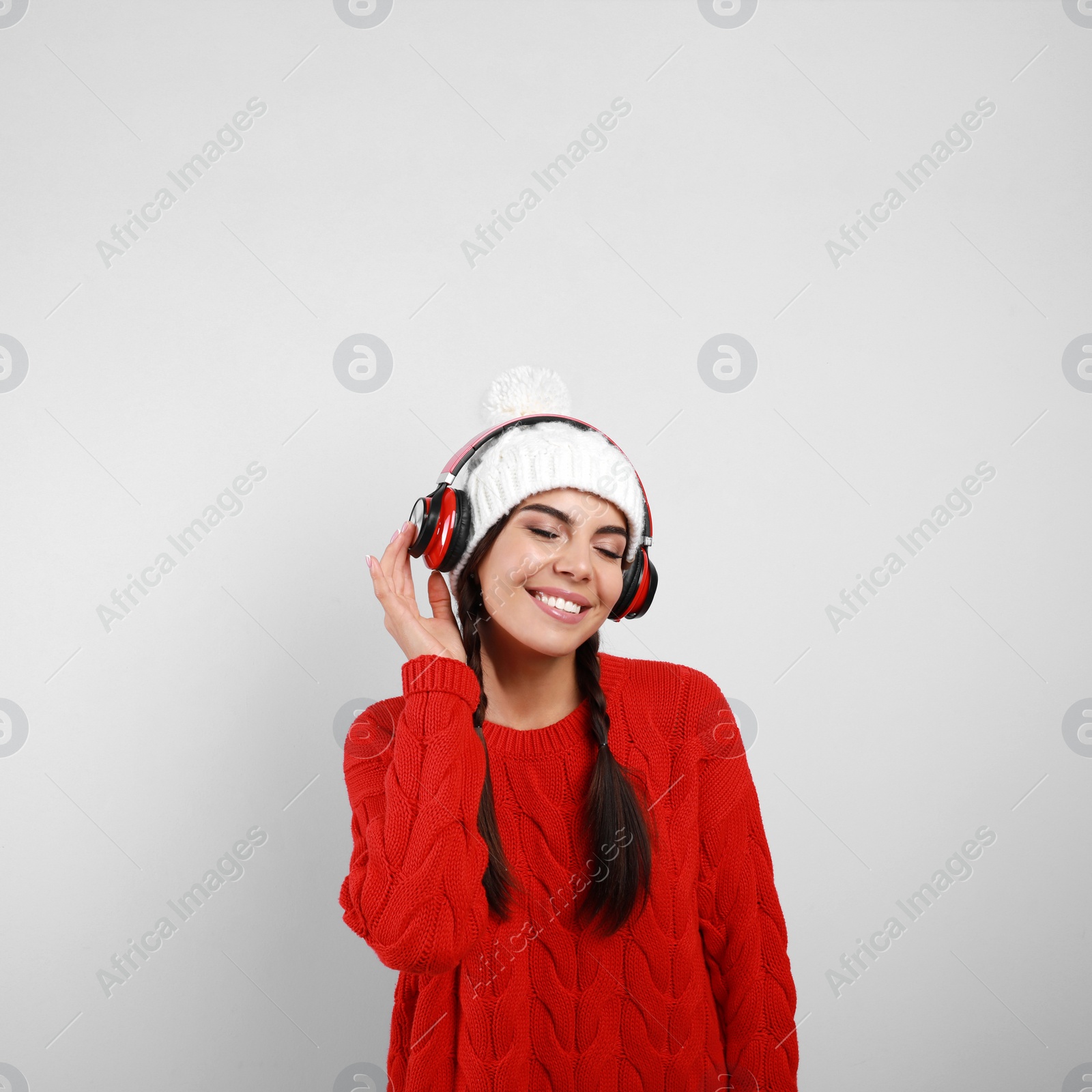 Photo of Young woman listening to music with headphones on grey background