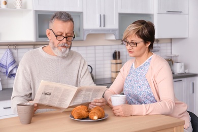 Photo of Happy senior couple having breakfast together at home