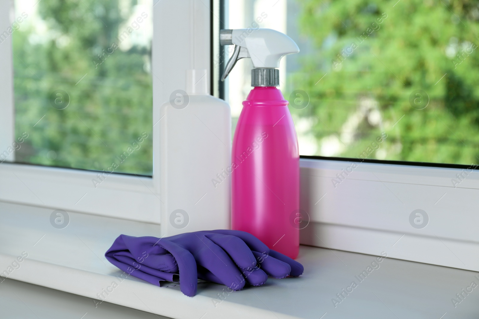 Photo of Bottles of detergents and gloves on window sill indoors