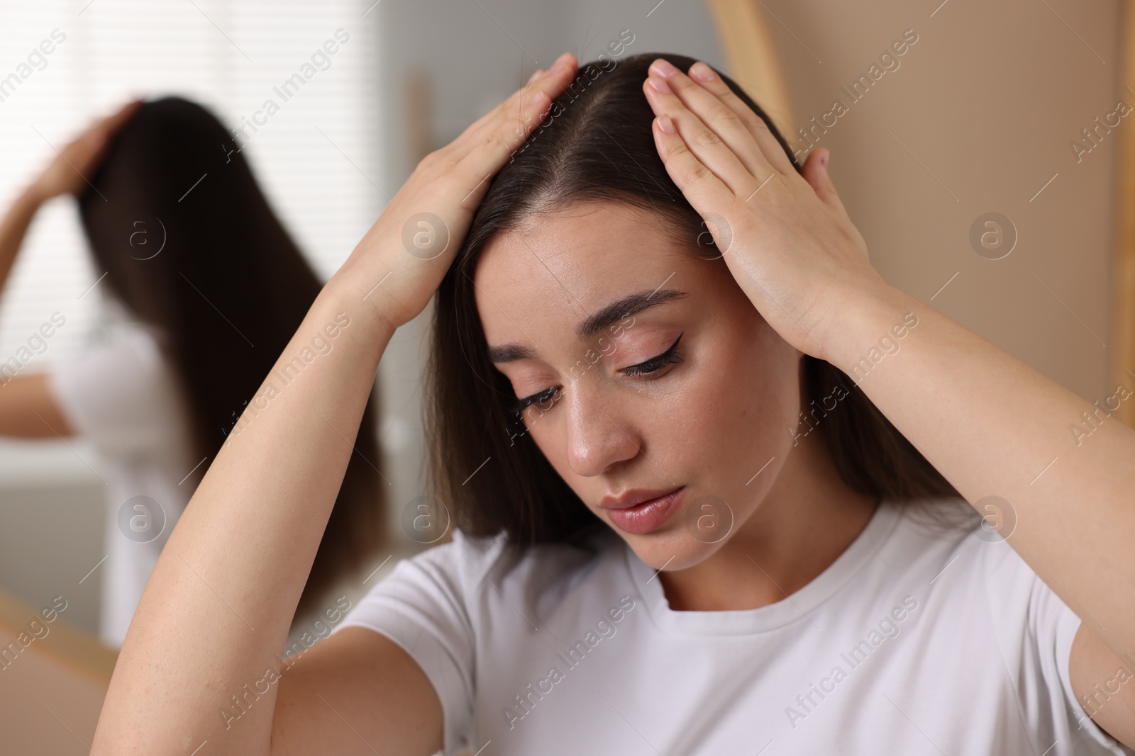 Photo of Woman examining her hair and scalp indoors
