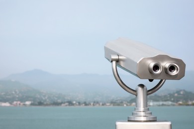 Photo of Metal tower viewer installed near sea, space for text. Mounted binoculars