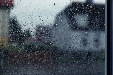 Photo of Window glass with water drops, closeup. Rainy weather