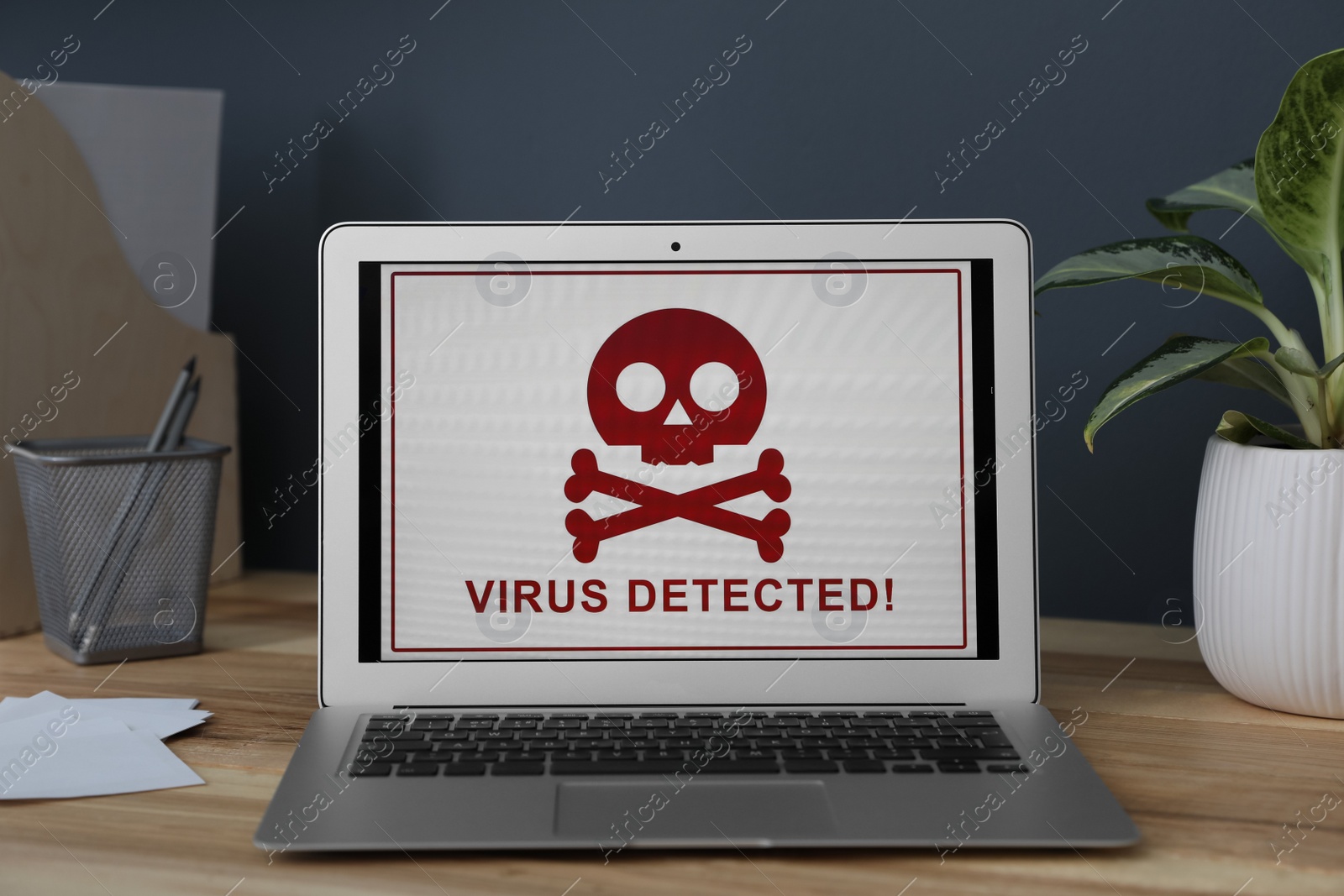 Photo of Laptop with warning about virus attack on wooden table in office