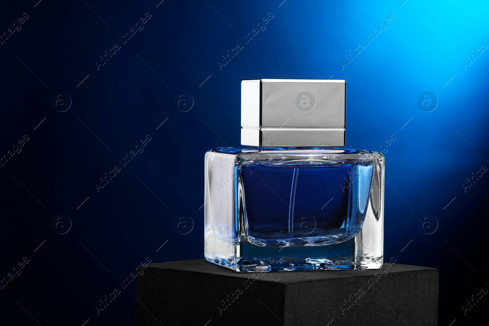 Photo of Luxury men`s perfume in bottle against dark blue background, space for text